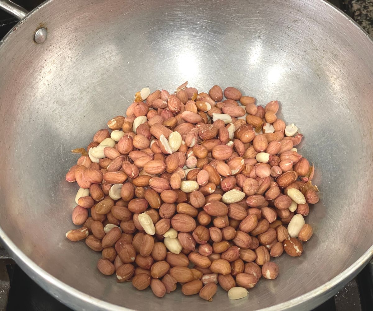 A large pan is with peanuts over the flame.