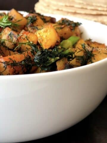 A bowl is with dill leaves and potato fry is on the table