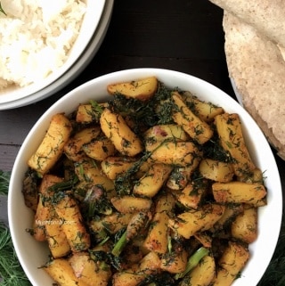 A bowl of potato fry with dill leaves is on the table