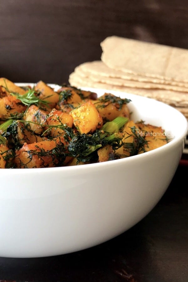 A bowl of potato fry with dill leaves is on the table