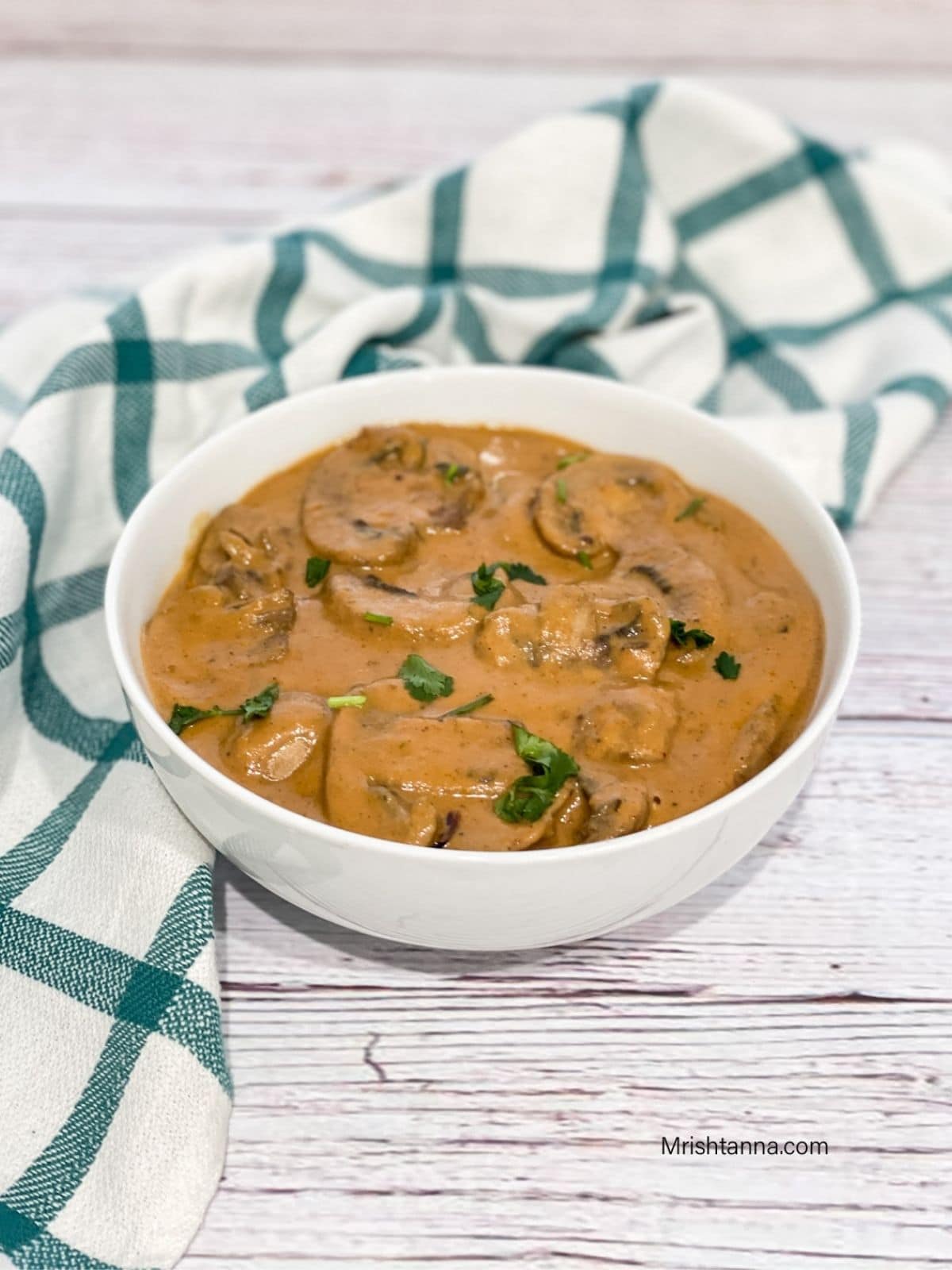 A bowl of mushroom masala is on the table.
