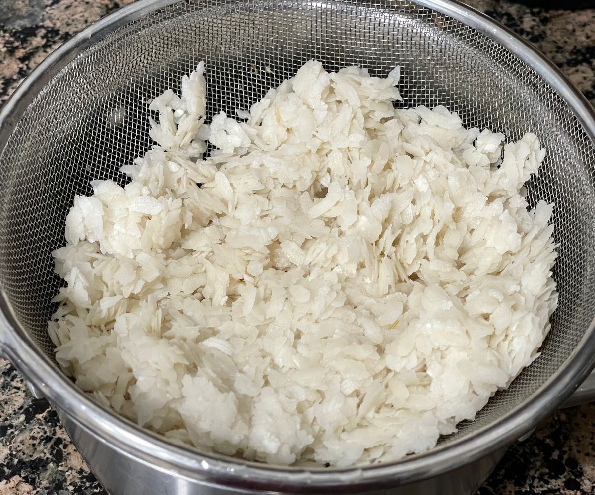 A colander is with washed medium thick poha.