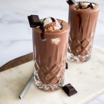 A tall glass is with vegan chocolate milkshake.