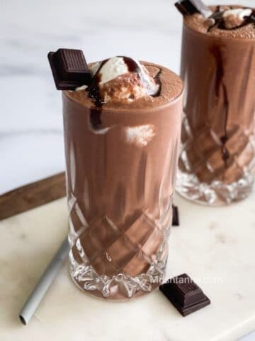 A tall glass is with vegan chocolate milkshake.