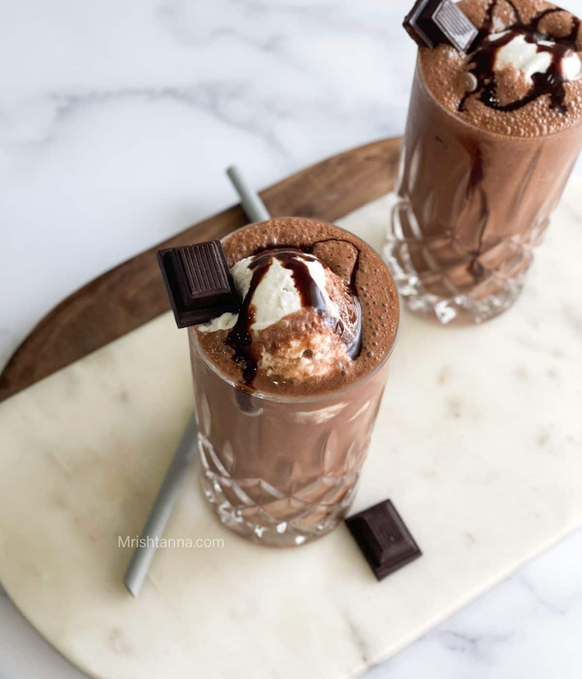 Head shot of vegan chocolate milkshake which is topped with ice cream and syrup.