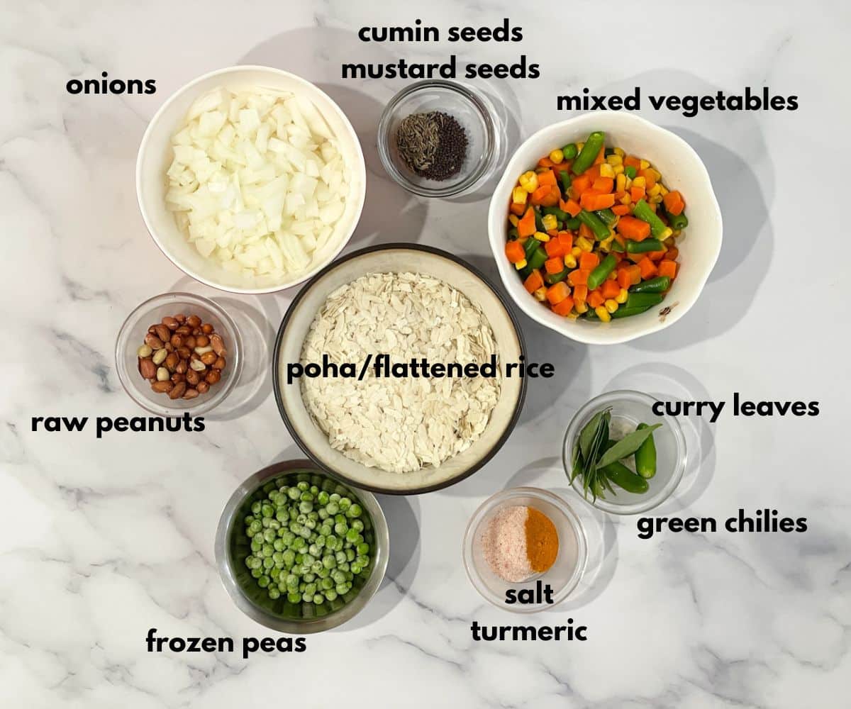 A surface is filled with bowls and plates of vegetable poha ingredients.