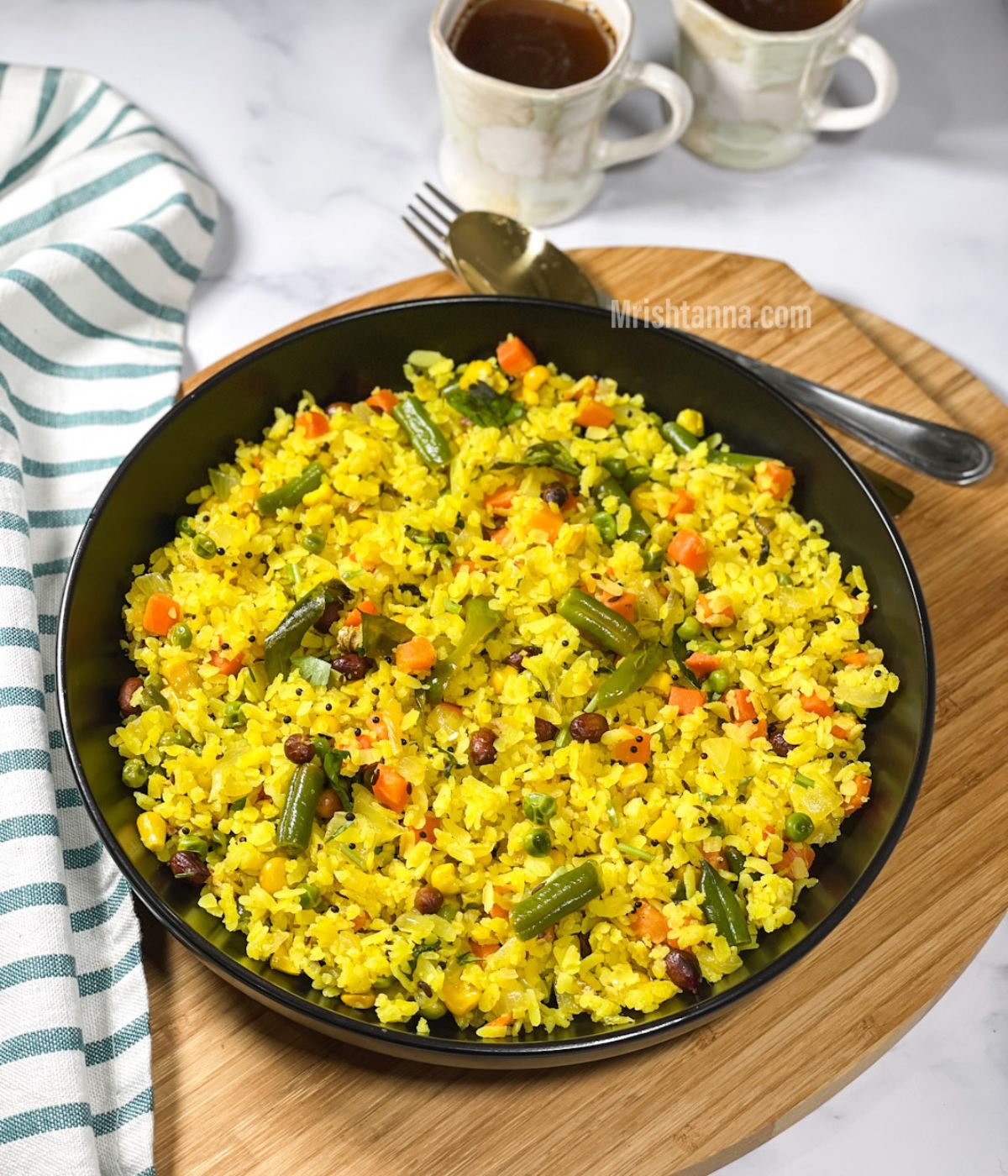 A plate is with vegetable poha and plcae don the wooden tray with a spoon.