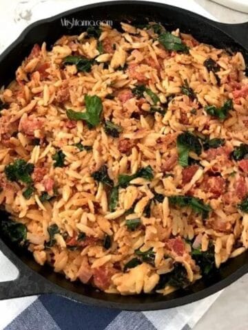 A pan is with creamy tomato orzo on the table.
