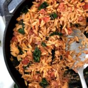 A pan is filled with tomato kale orzo