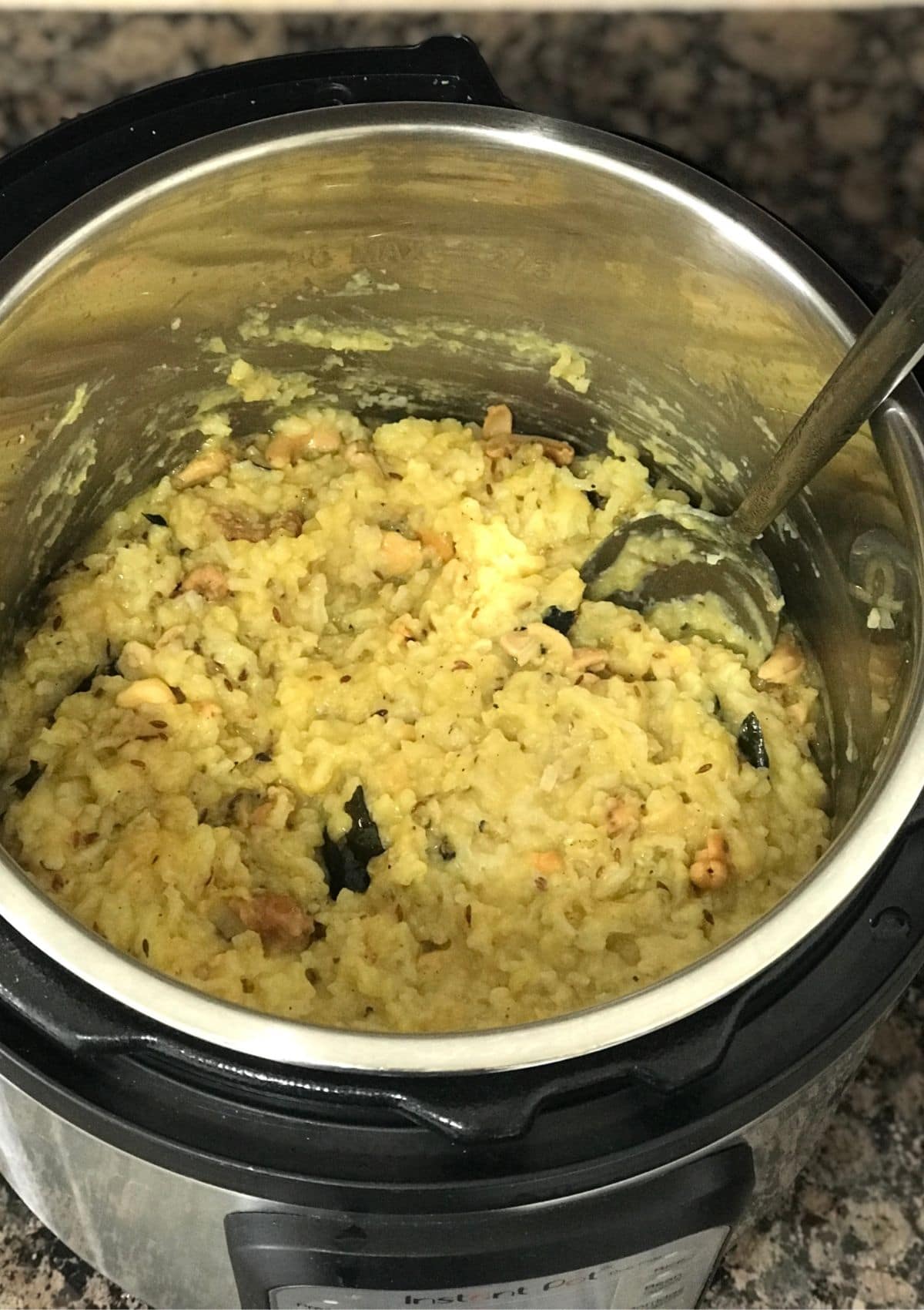 an instant pot with khara pongal and inserted big spoon