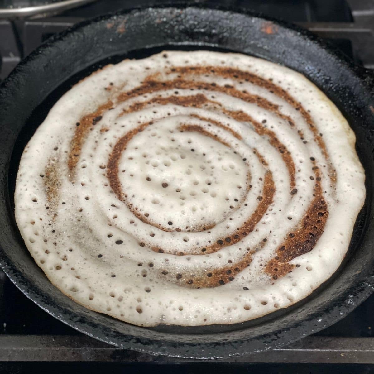 A pan is with dosa over the heat 