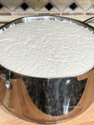 A steel vessel is filled with fermented dosa batter over the counter top.