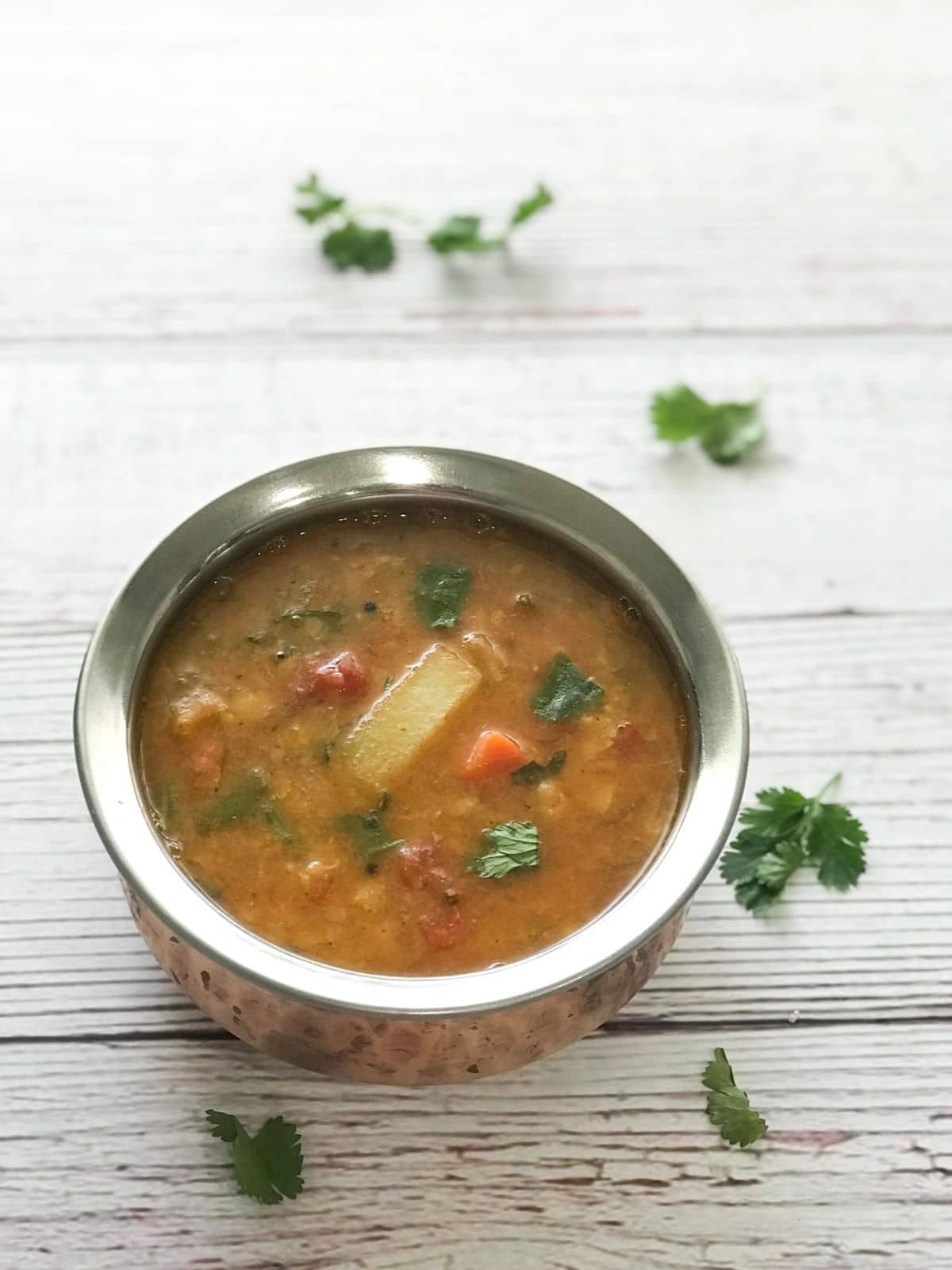 A copper pot is with sambar placed on the table