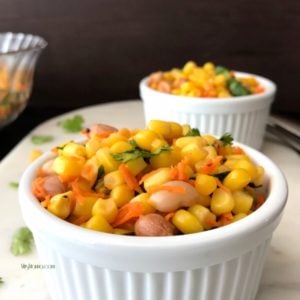 A bowl of food on a plate, with Corn salad