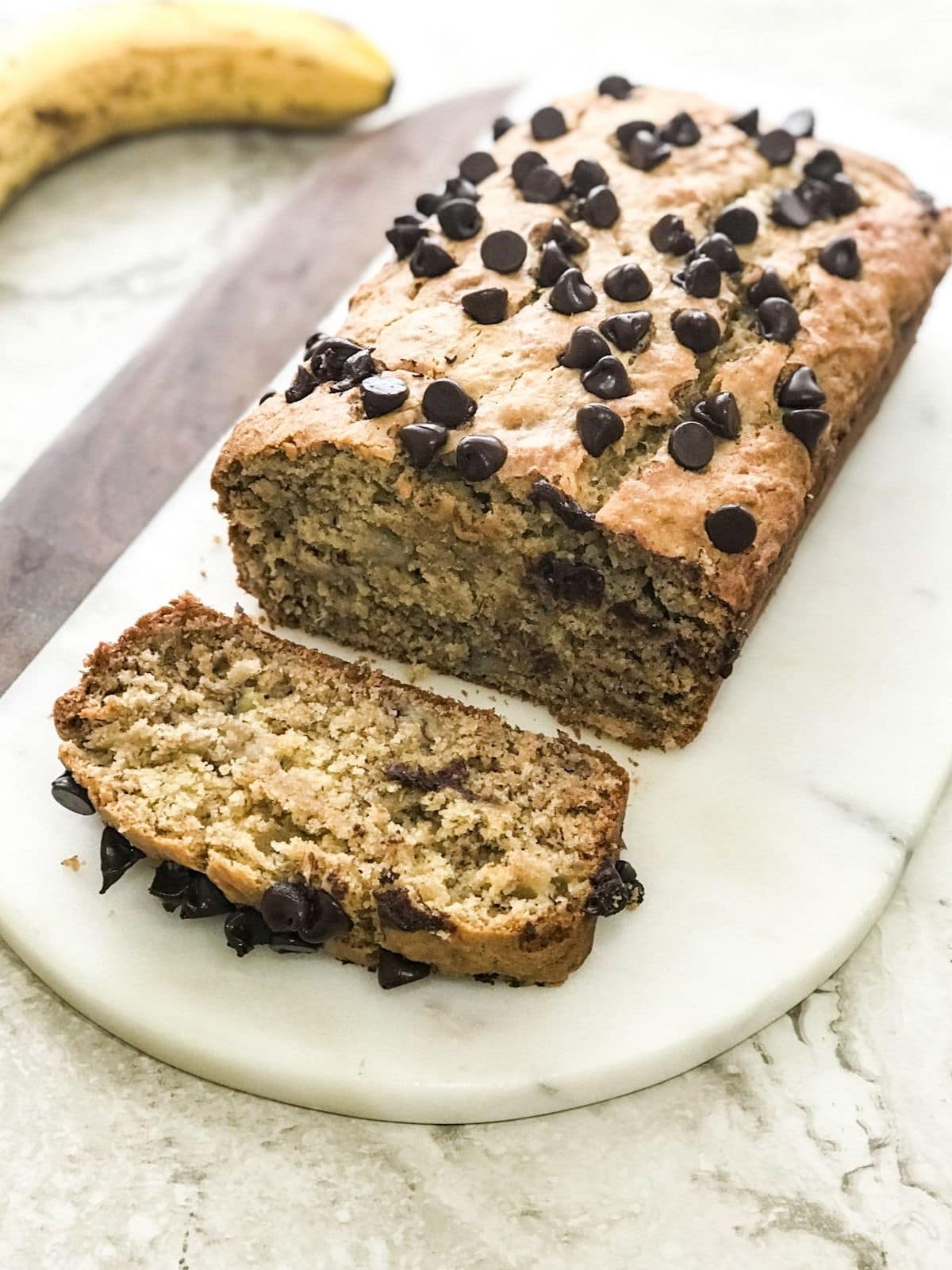 A banana bread loaf is on the white serving tray