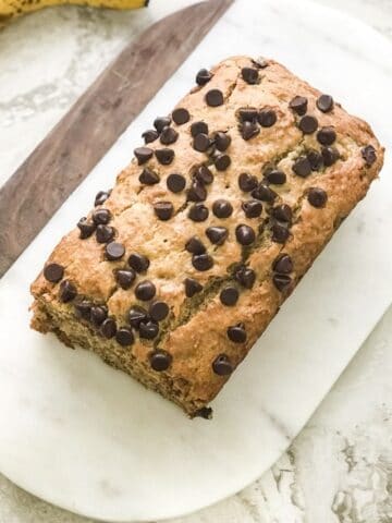 A banana bread loaf is on the white serving tray