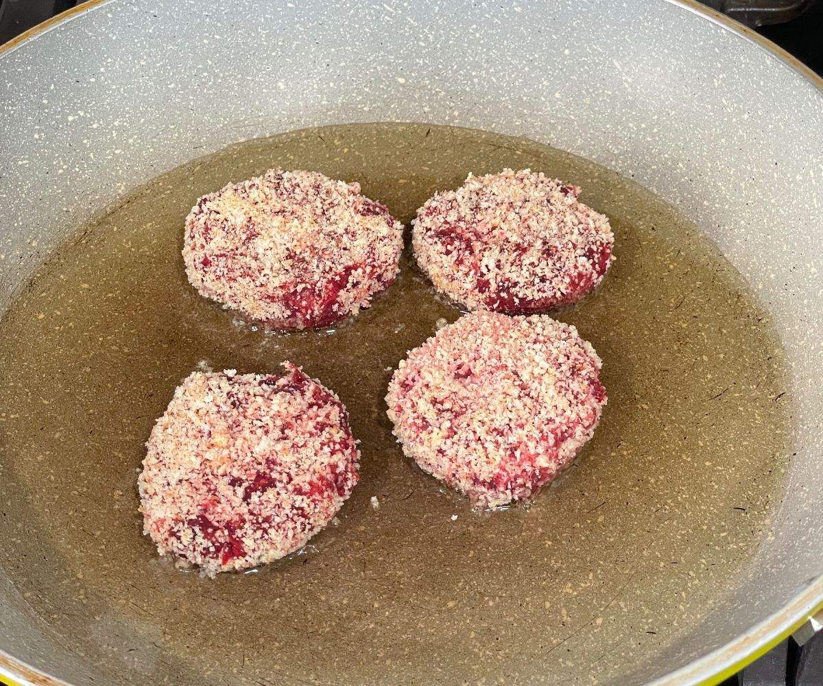 A pan is with beetroot cutlets over the heat.