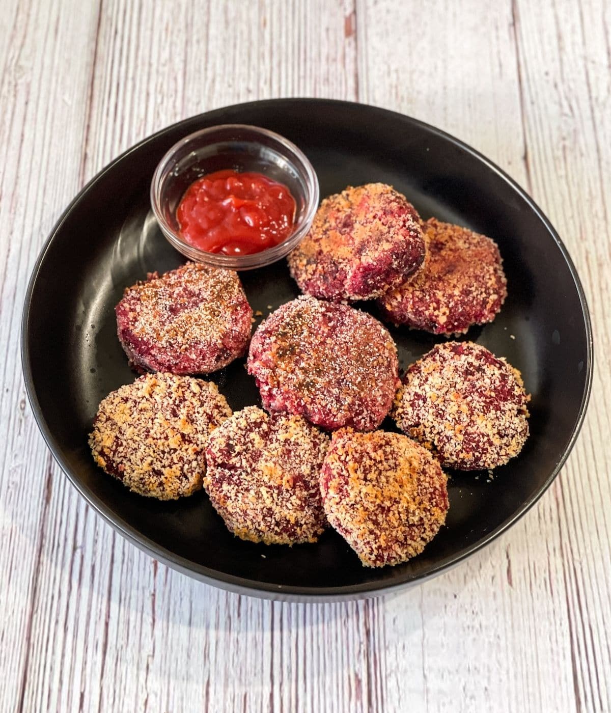 A plate is with beetroot cutlets and tomato ketchup.