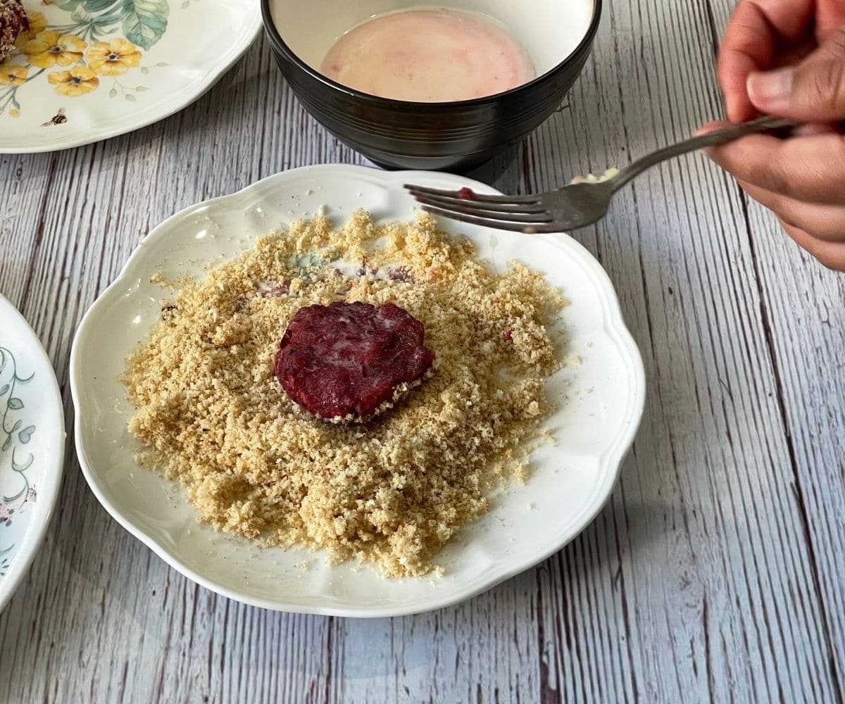 A beetroot raw cutlets is on the breadcrumbs bed.