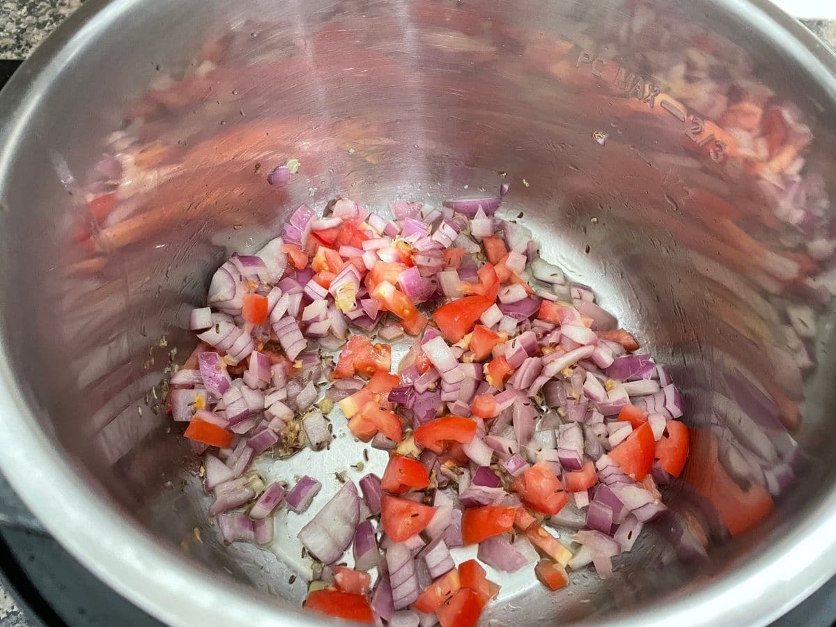 A pot is with tomatoes and spices for khichdi