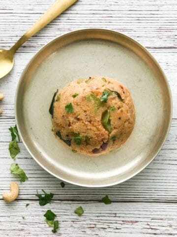 A silver plate is filled with khara bath and topped with cilantro