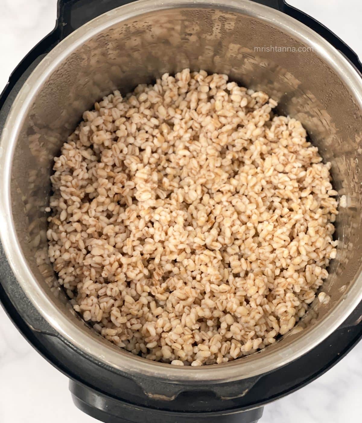An instant pot has cooked pearl barley.