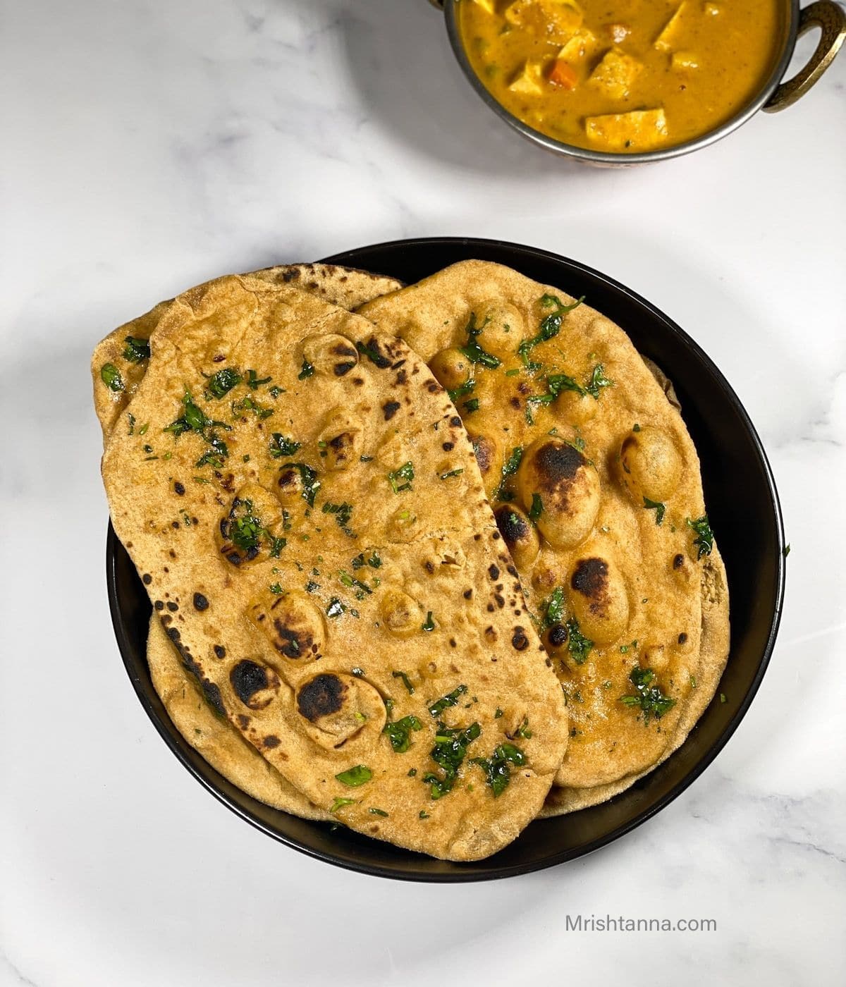 A plate is with stacked vegan wheat naan bread.