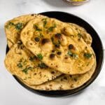 A plate of whole wheat naan is on the table along with curry.