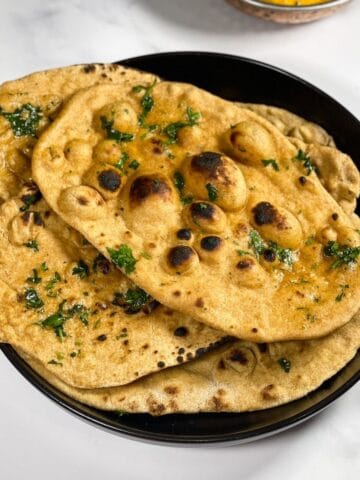 A plate of whole wheat naan is on the table along with curry.