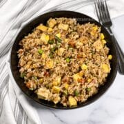 A plate of vegan fried rice is on the table with forks.