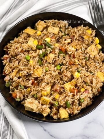 A plate of vegan fried rice is on the table with forks.