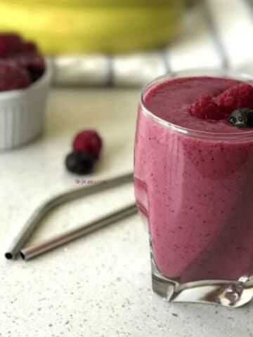 A glass jar is with berry smothie and its on the table