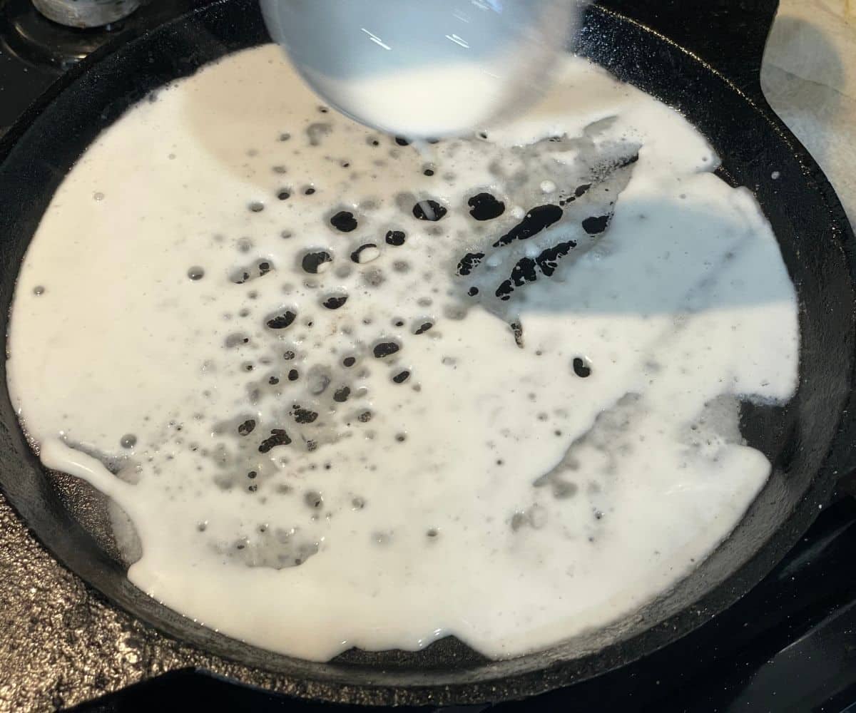 Heated cast iron has poured neer dosa batter.