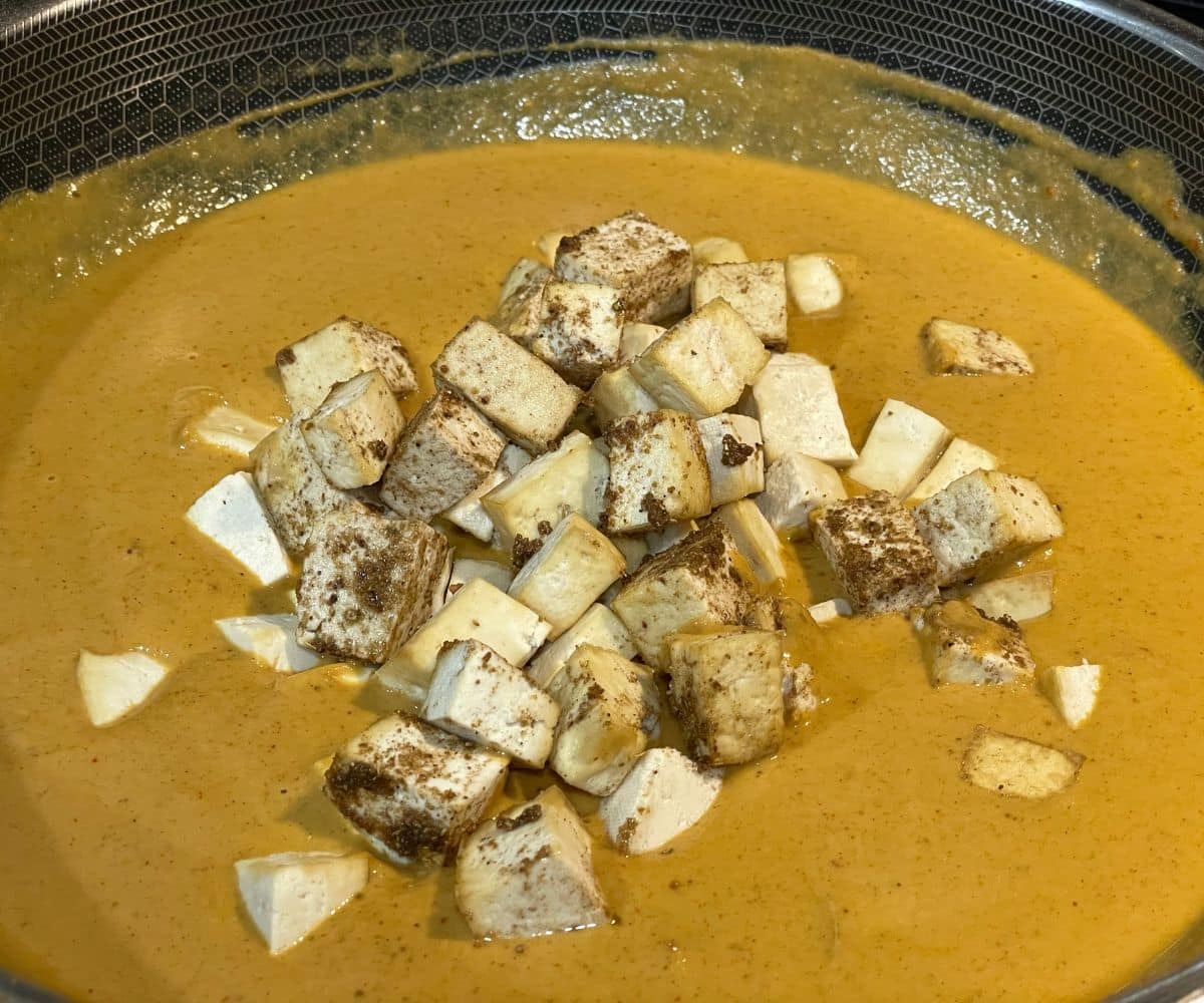 A pan is with vegan tofu butter masala curry over the heat.