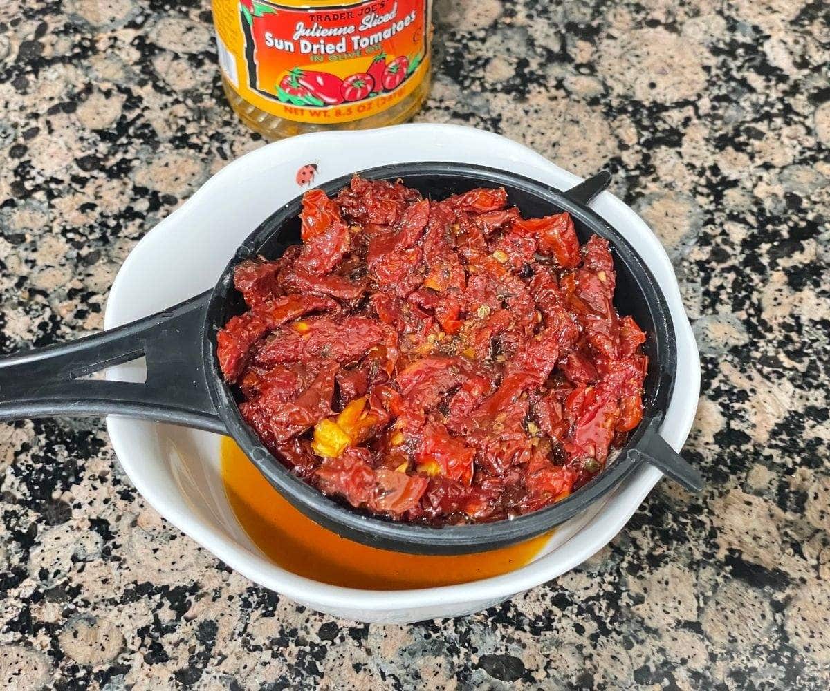 A strainer is with sun dried tomatoes. 