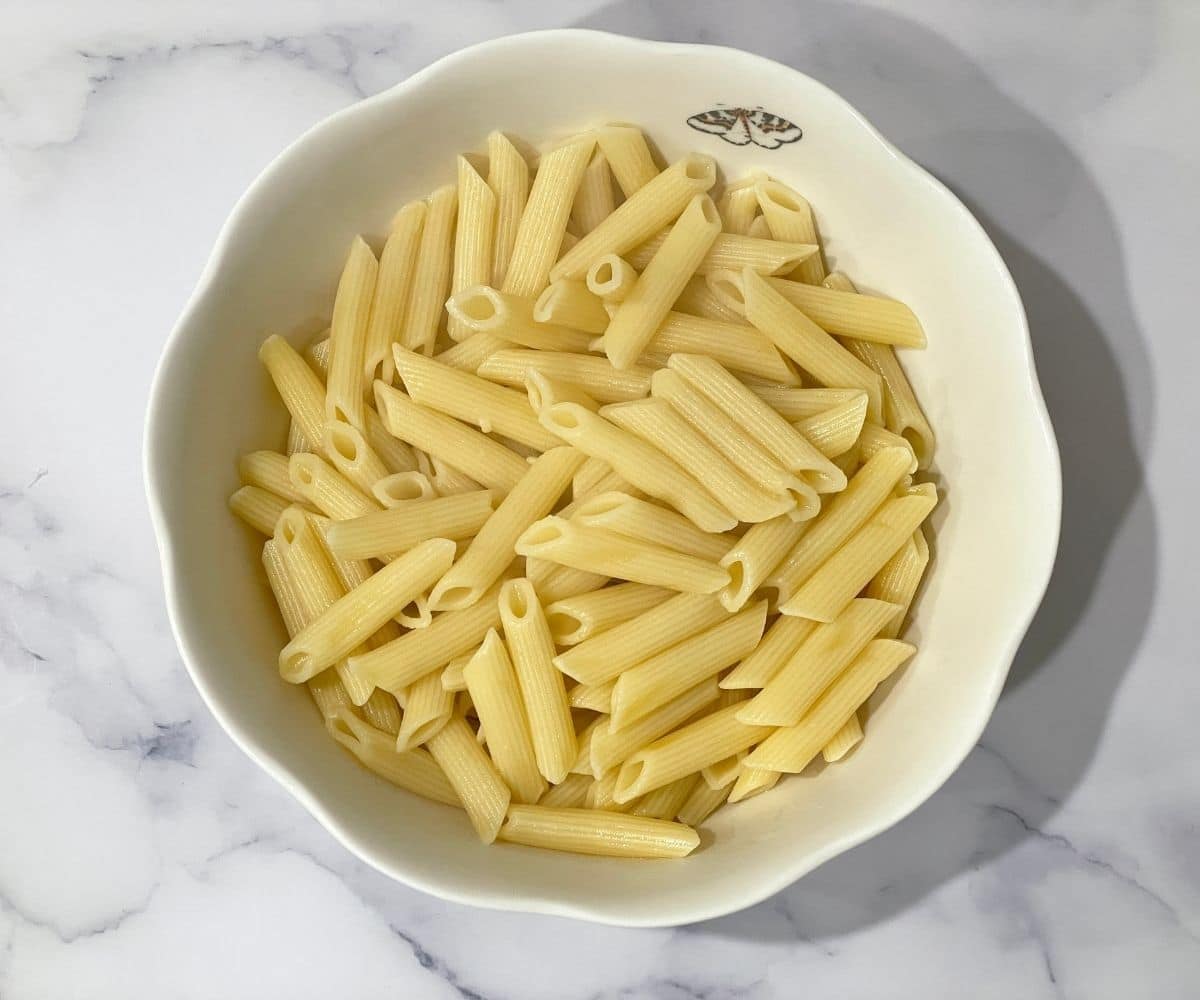 Cooked penne pasta is in the bowl