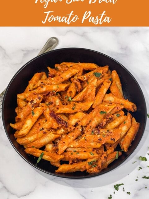 A plate of vegan sun dried tomato pasta is on the table.