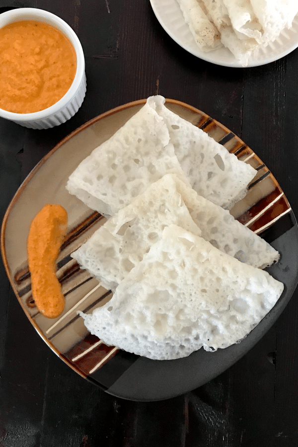  A plate of neer dosa and red chutney is on the table