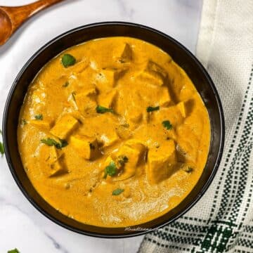 A bowl is filled with vegan tofu butter masala curry.