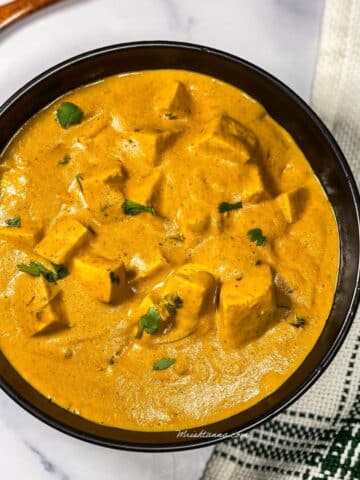 A bowl is filled with vegan tofu butter masala curry.