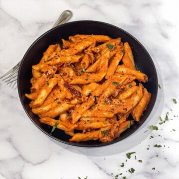 A plate is filled with sun dried tomato pasta.