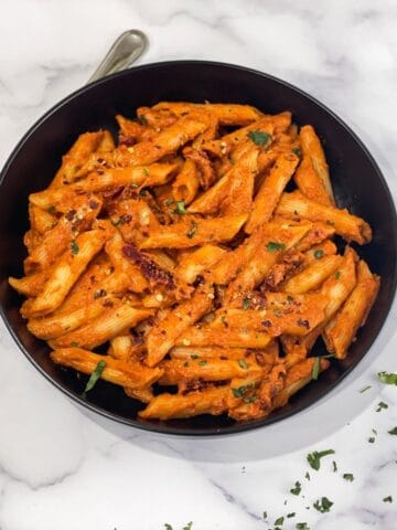 A plate is filled with sun dried tomato pasta.
