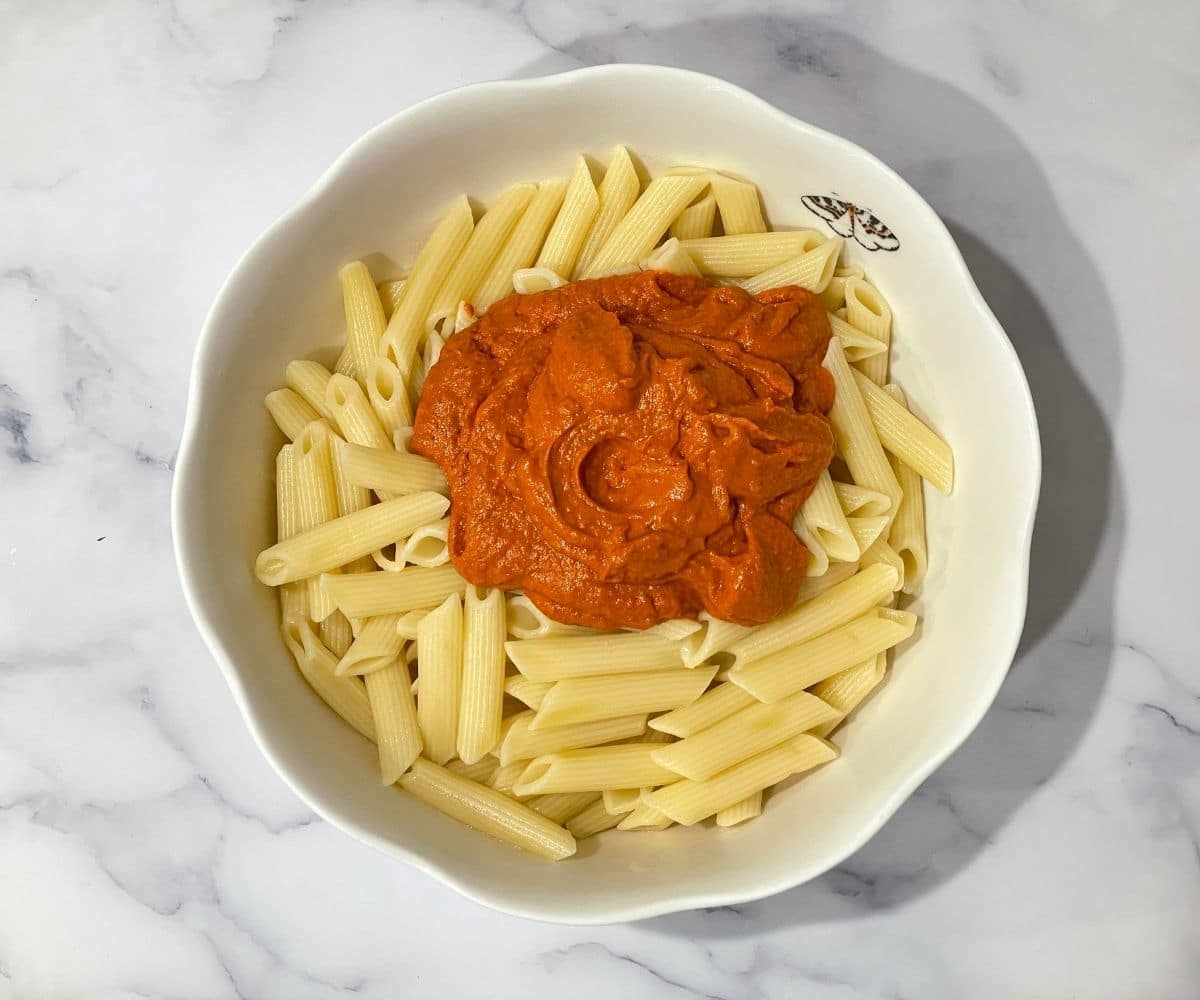 A bowl is with Penne pasta and sauce.