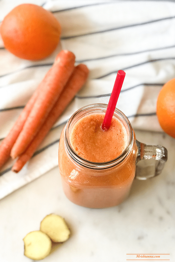 A glass jar is filled with orange carrot Smoothie