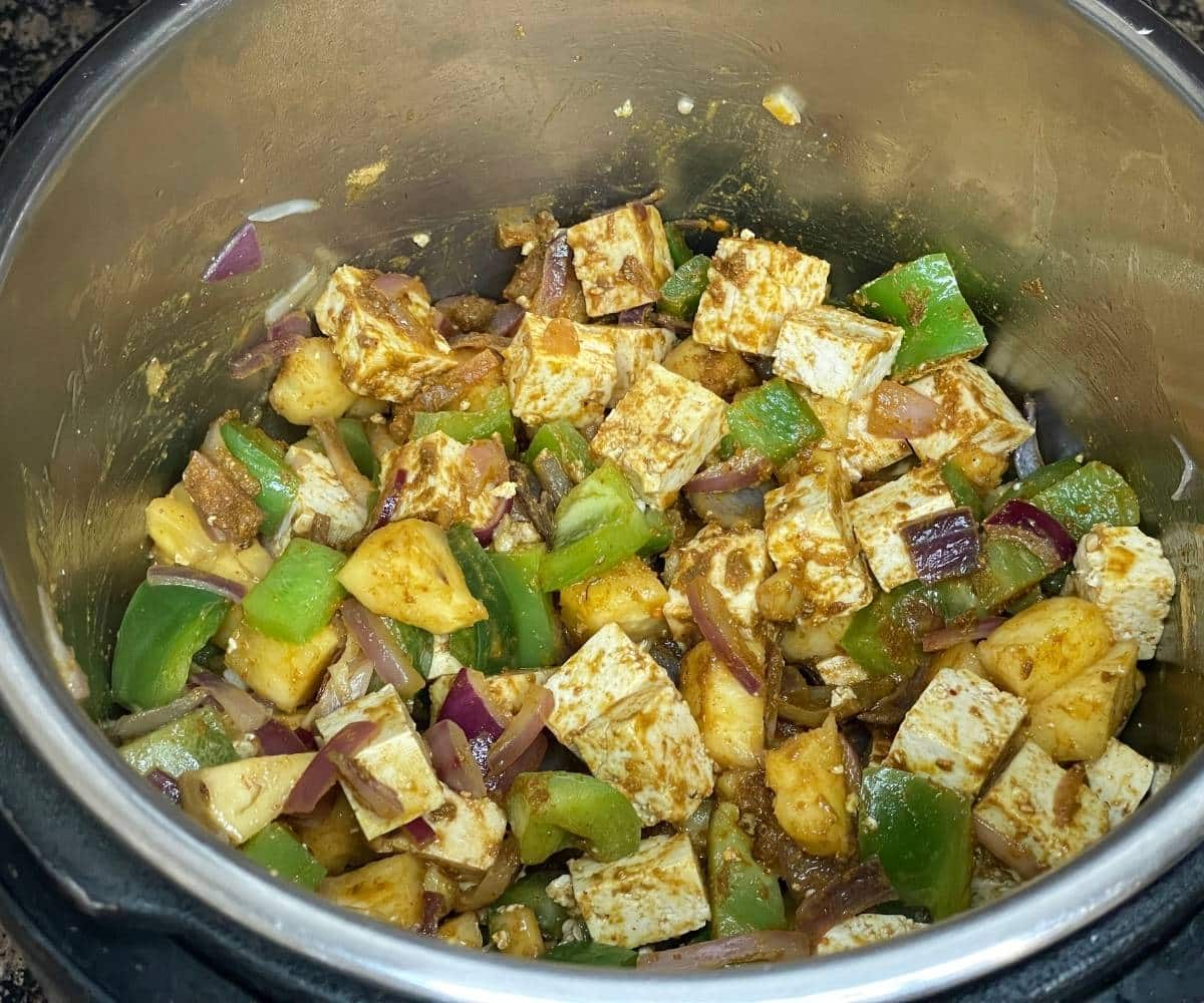 An instant pot has all the ingredients on saute mode to cook Thai fried rice.