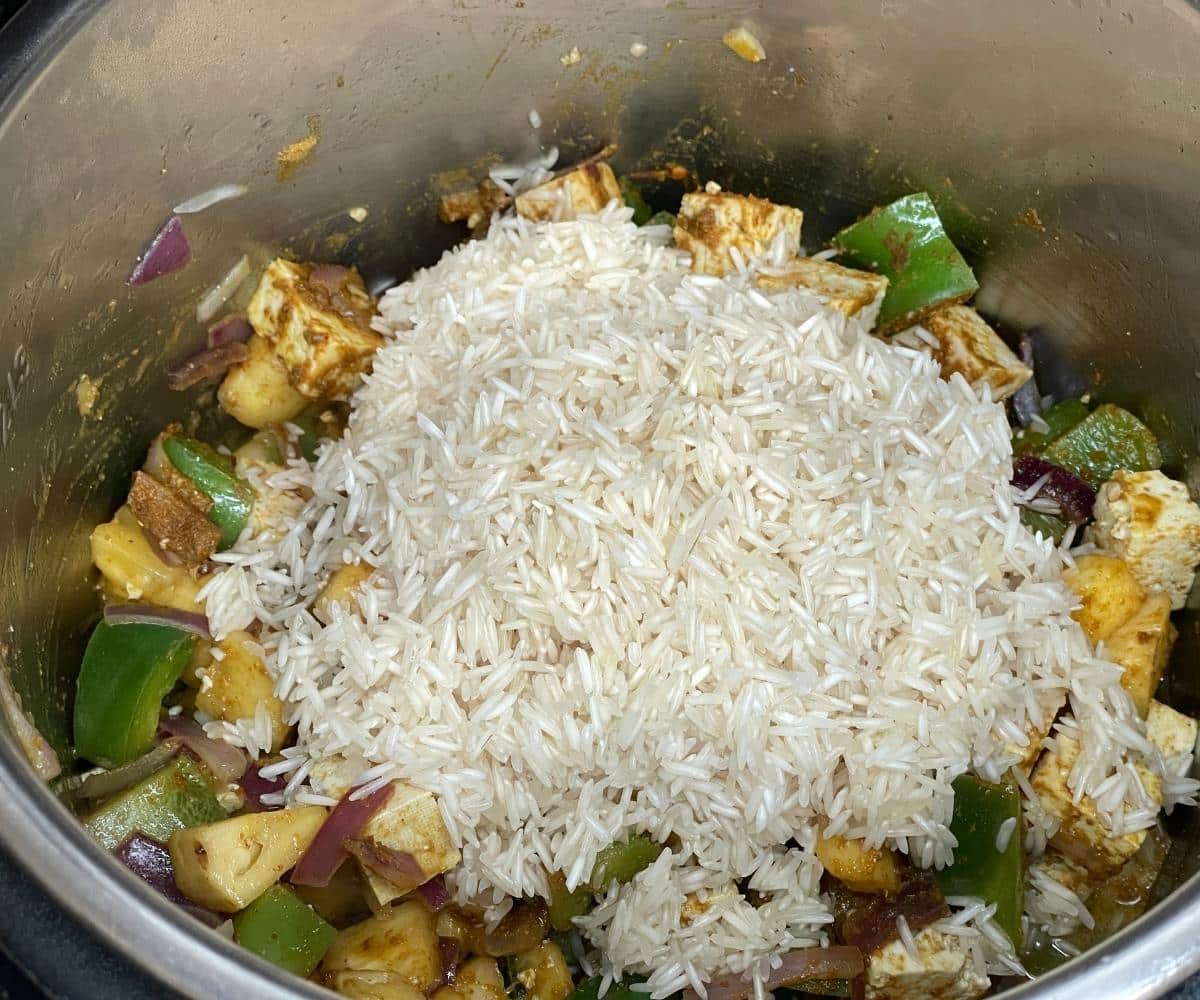 An instant pot has all the ingredients on saute mode to cook Thai pineapple fried rice.