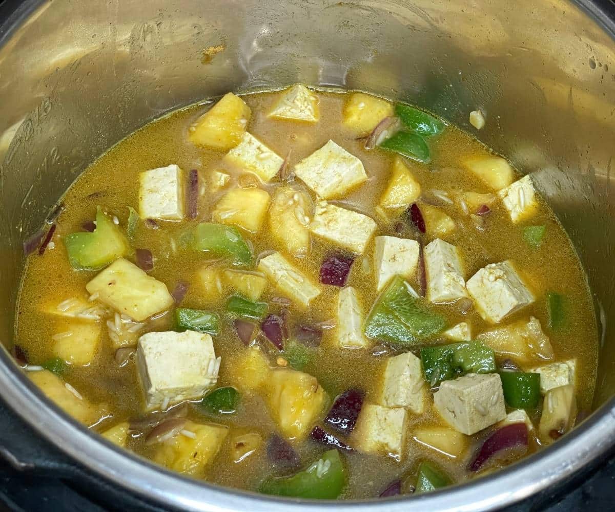 An instant pot has all the ingredients on saute mode to cook Thai fried rice.