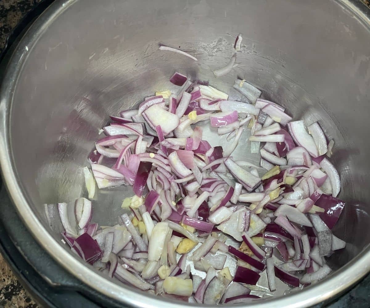 An instant pot has onions, garlic and ginger for pineapple rice.