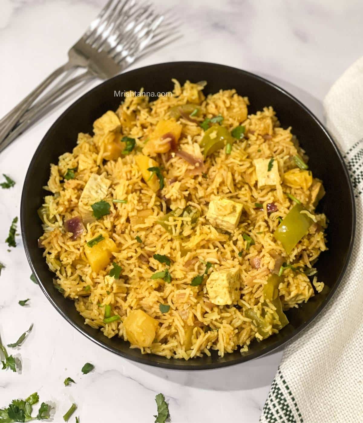 A plate of pineapple fried rice is on the marble table.