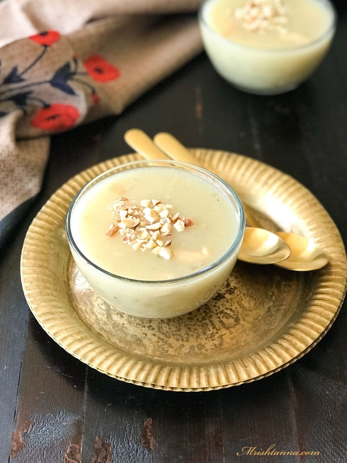 A glass bowl is with sabudana kheer and topped with crushed nuts